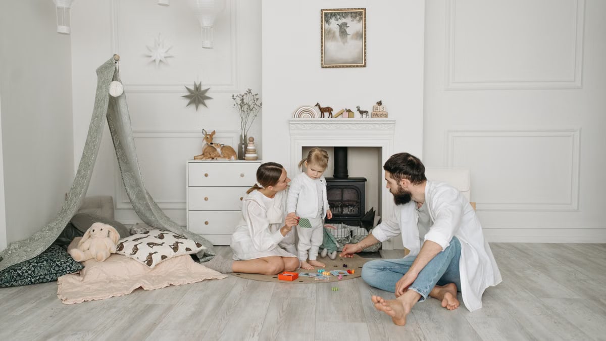 Warm family scene of parents playing with their daughter in a cozy white room.